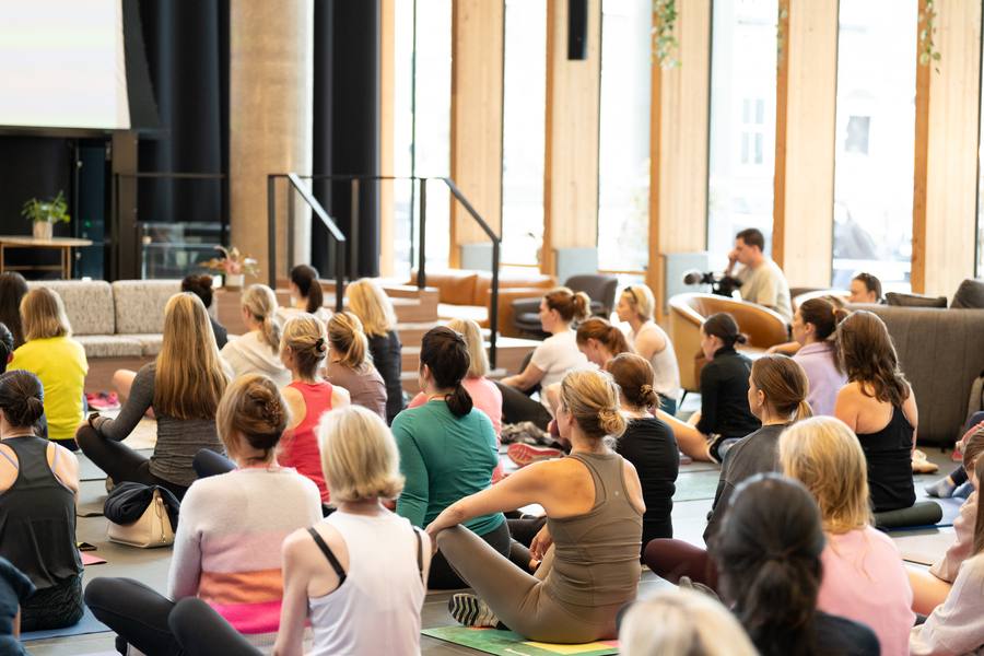 Women seated on yoga mats during yoga with Miriam Hussey at the SISTERLY Summit